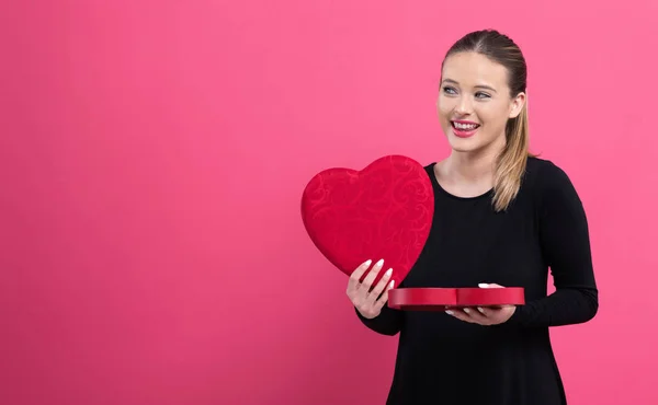 Mujer joven sosteniendo una gran caja de regalo de corazón —  Fotos de Stock