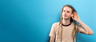 Genç adam sağlam bir arka plan üzerinde dinleme