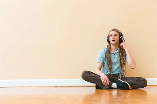 Homem ouvindo fones de ouvido em uma sala grande — Fotografia de Stock