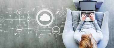 Modern bir gri sandalyede bir dizüstü bilgisayar kullanan adam ile bulut