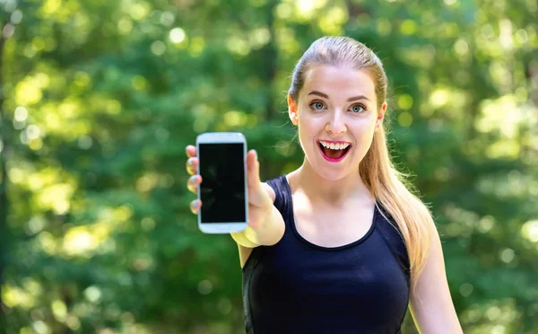 Jonge vrouw stak een telefoon in haar hand — Stockfoto