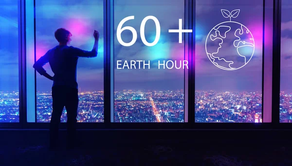 Earth hour with man by large windows at night