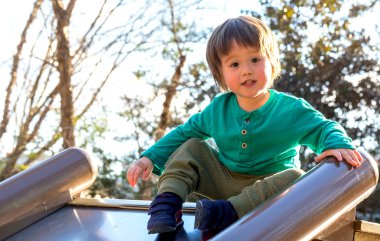 Bir slayt üzerinde oynarken yürümeye başlayan çocuk