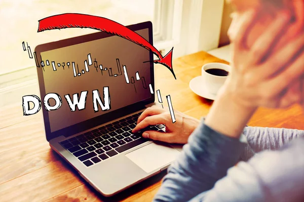 Market down trend chart with man using a laptop