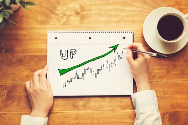 Market up gráfico de tendências com uma pessoa segurando uma caneta — Fotografia de Stock