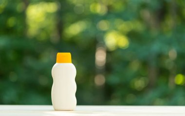 Orman arka planında güneş kremi şişesi