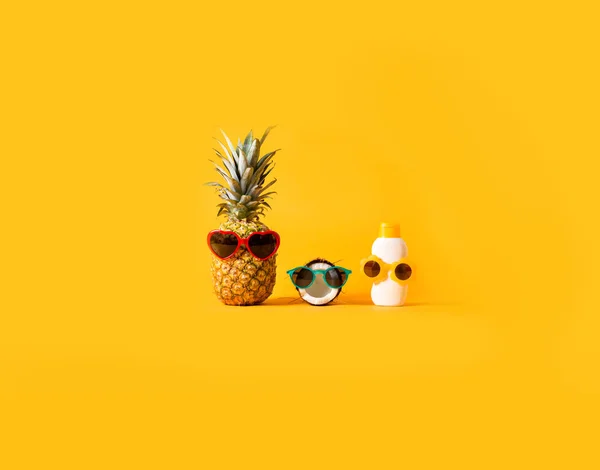 Pineapple and coconut wearing sunglasses with sunblock — Stock Photo, Image