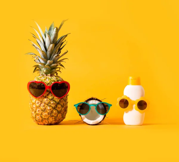 Pineapple and coconut wearing sunglasses with sunblock — Stock Photo, Image