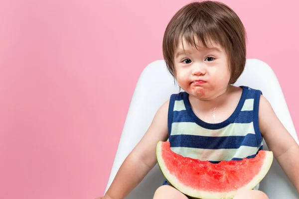 Småbarn äter vattenmelon på en rosa bakgrund — Stockfoto