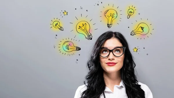 Idea light bulbs with young businesswoman — Stock Photo, Image