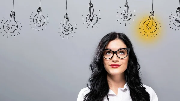 Idea light bulbs with young businesswoman — Stock Photo, Image