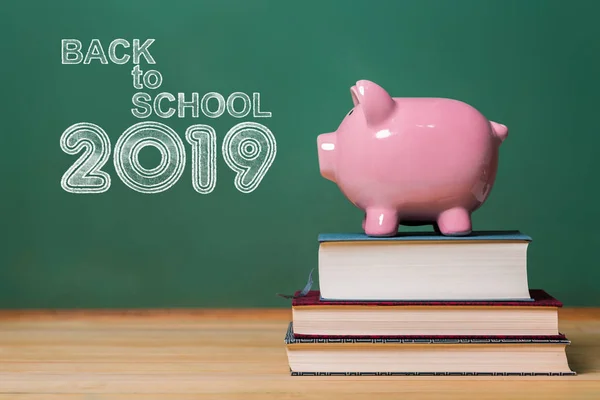 Back to School 2019 testo con salvadanaio rosa in cima ai libri — Foto Stock