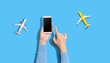 Elinde uçaklarla akıllı bir telefon tutan kişi.