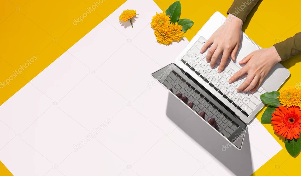 Person using a laptop computer with autumn flowers