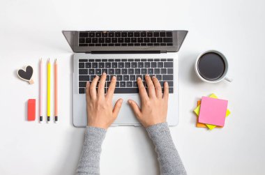 Ofis malzemesi olan bir dizüstü bilgisayar kullanan kişi.