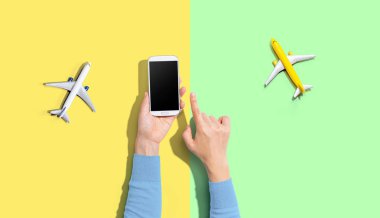 Elinde uçaklarla akıllı bir telefon tutan kişi.
