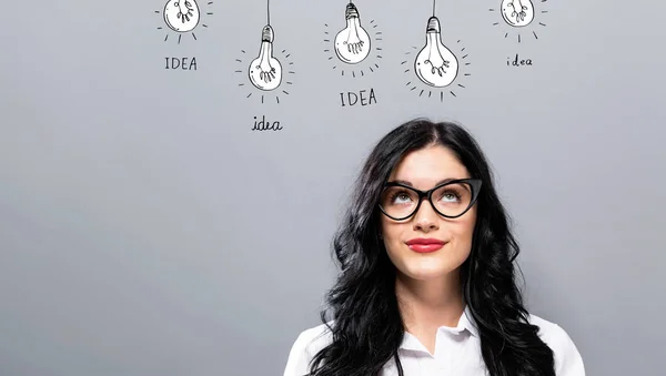 Idea light bulbs with young businesswoman — Stock Photo, Image