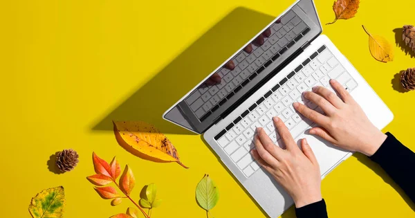 Person, die einen Laptop mit Herbstblättern benutzt — Stockfoto