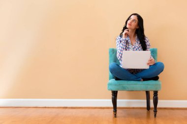 Düşünceli bir poz bir dizüstü bilgisayar ile genç kadın