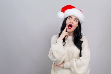 Noel Baba şapkalı genç bayan düşünceli.