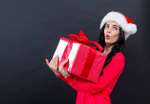 Young woman with santa hat holding a gift box — Stock Photo, Image