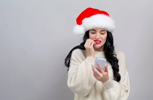 Jeune femme dans un chapeau de Père Noël en utilisant son téléphone intelligent — Photo