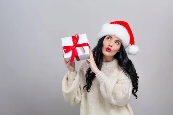 Noel Baba şapkalı genç bir kadın elinde bir hediye kutusu tutuyor. — Stok fotoğraf