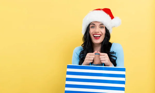 Mladá žena se Santa klobouk drží nákupní tašku — Stock fotografie