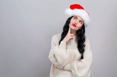 Noel Baba şapkalı genç bayan düşünceli.