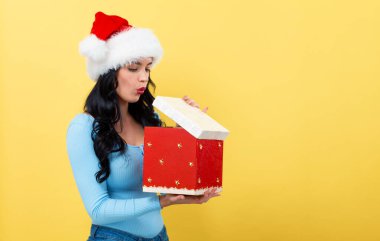 Genç bir kadın Noel hediyesi kutusunu açıyor.