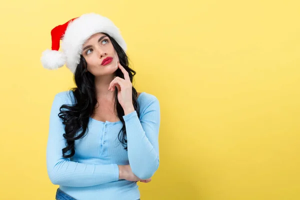 Jovem mulher com chapéu de Papai Noel postura pensativa — Fotografia de Stock
