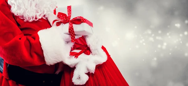 Der Weihnachtsmann hält eine Geschenkschachtel aus einem roten Sack — Stockfoto
