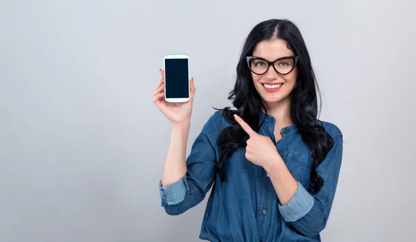 Ung kvinna håller ut en telefon i handen — Stockfoto