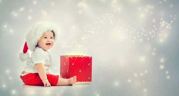 带圣诞老人帽子的幼儿男孩打开礼品盒 — 图库照片