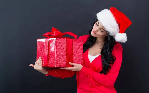 Young woman with santa hat holding a gift box — Stock Photo, Image