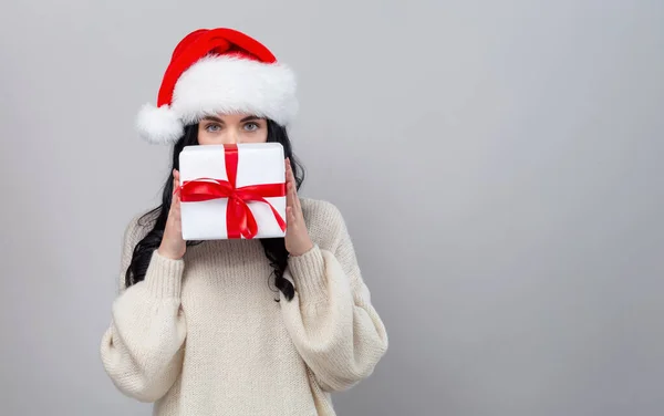 Ung kvinna med tomte hatt hålla en presentförpackning — Stockfoto