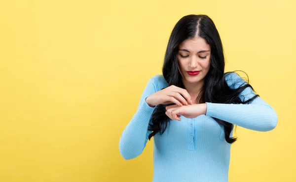 Mujer joven arañándose el brazo con picazón . — Foto de Stock