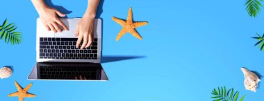 Yaz temalı nesneleri olan bir dizüstü bilgisayar kullanan kişi