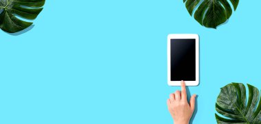 Tropikal yapraklı tablet bilgisayar kullanan kişi