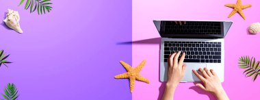 Yaz temalı nesneleri olan bir dizüstü bilgisayar kullanan kişi