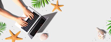 Yaz temalı nesneleri olan bir dizüstü bilgisayar kullanan kişi