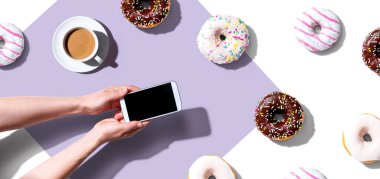 Akıllı telefon ve donut kullanan biri.