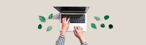 Person, die einen Laptop mit grünen Blättern benutzt — Stockfoto