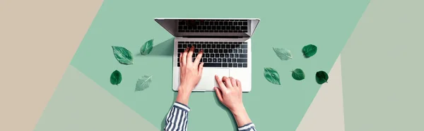 Person using a laptop computer with green leaves — Stock Photo, Image