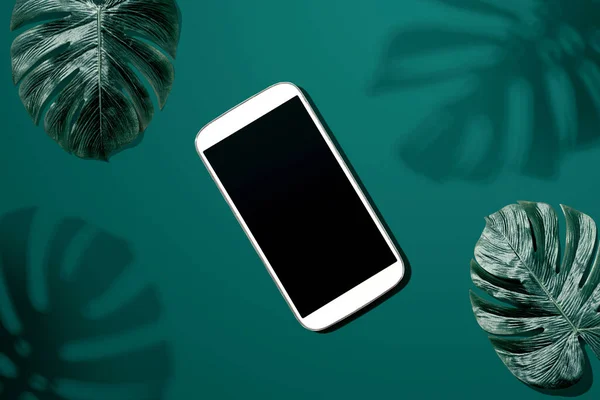 Smartphone met tropische monstera bladeren en schaduw — Stockfoto