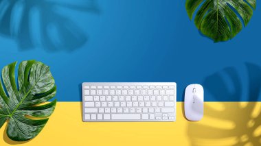 Tropikal yaprakları ve gölgesi olan bilgisayar klavyesi