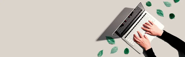 Osoba korzystająca z laptopa z zielonymi liśćmi — Zdjęcie stockowe