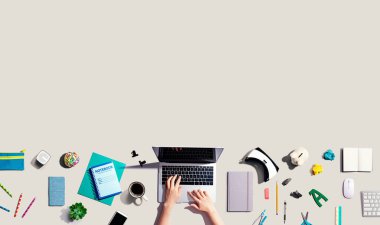 Ofis malzemesi olan bir dizüstü bilgisayar kullanan kişi.