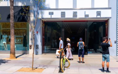 İnsanlar Santa Monica, CA 'da bir Tesla mağazasının önünden geçiyor.