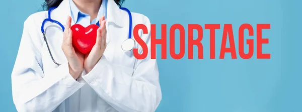 Shortage theme with a doctor holding a heart — Stock Photo, Image